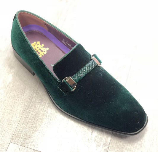 The After Midnight Formal Shoe 6753 Green from AFTER MIDNIGHT, featuring a dark green velvet slip-on design with a green strap and metallic buckle, rests on a light wooden floor.