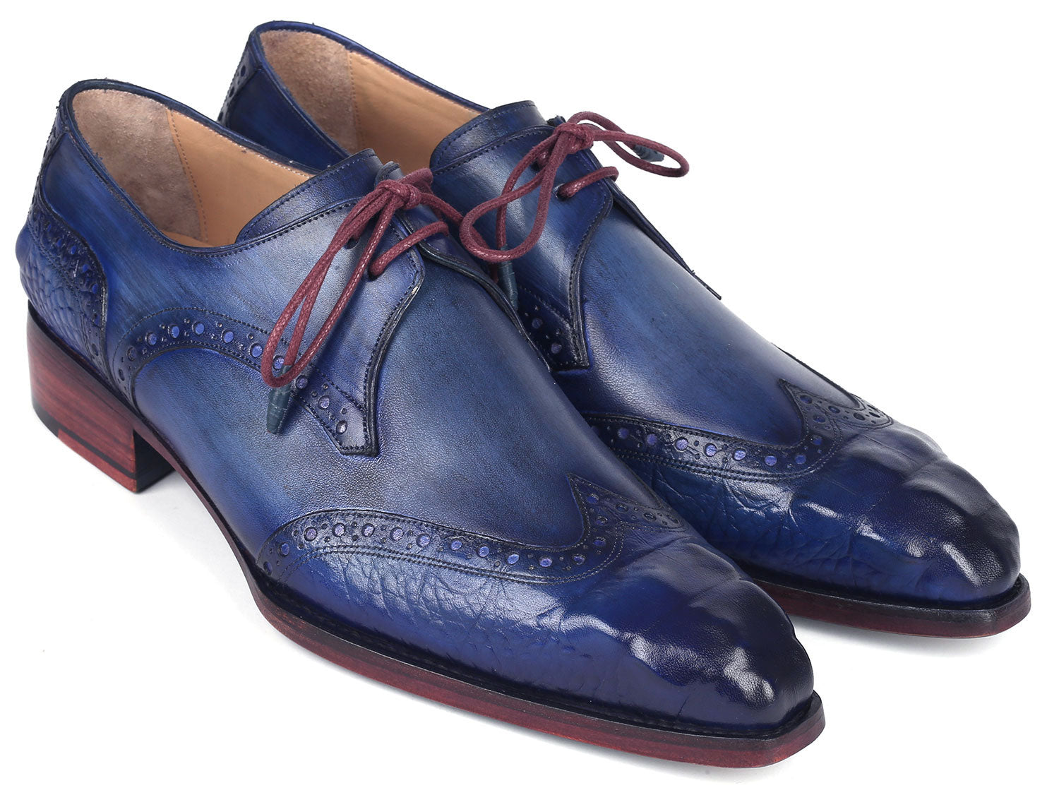 The Paul Parkman Goodyear Welted Wingtip Derby Shoes Blue & Navy - 584-BLU showcase a stunning design in blue leather with intricate detailing and vibrant red laces. Displayed beautifully, one shoe is elegantly laid on its side while the other stands upright. These meticulously handmade shoes feature the renowned Goodyear welted craftsmanship, ensuring both elegance and durability.