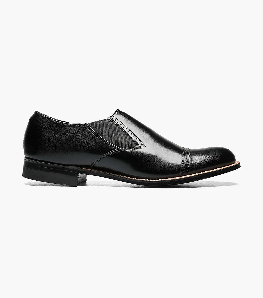 The Stacy Adams MADISON Cap Toe Slip On in black, designated as style number 00017-01, features a sophisticated cap-toe design with elastic side panels, complemented by a leather sole and sleek low heel.