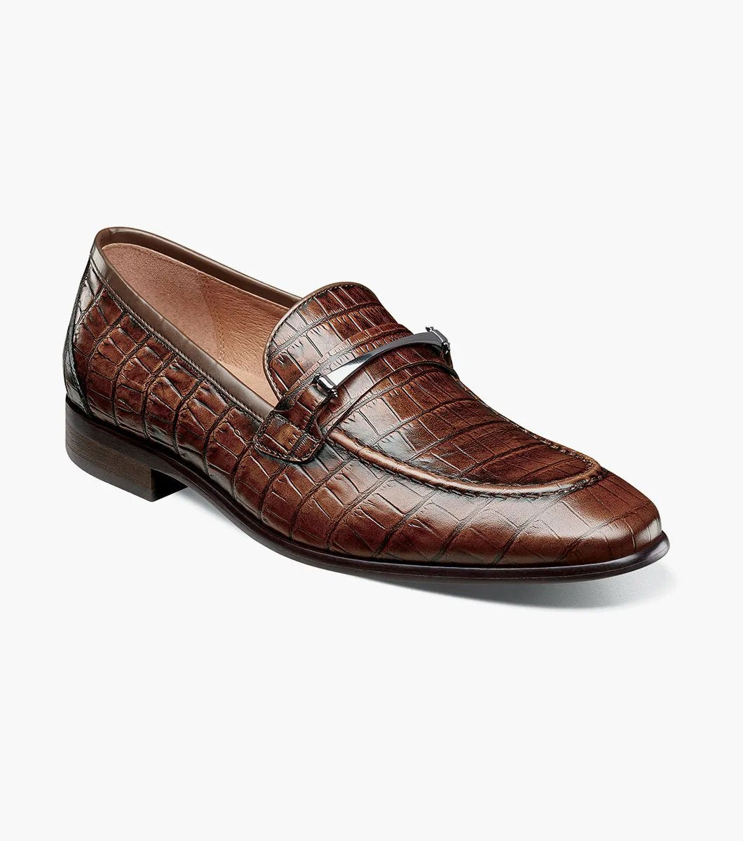The STACY ADAMS Ferdinand Moc Toe Bit Slip On in Cognac features croco print leather, a decorative metal bit, and a cushioned memory foam footbed, displayed on a white background.