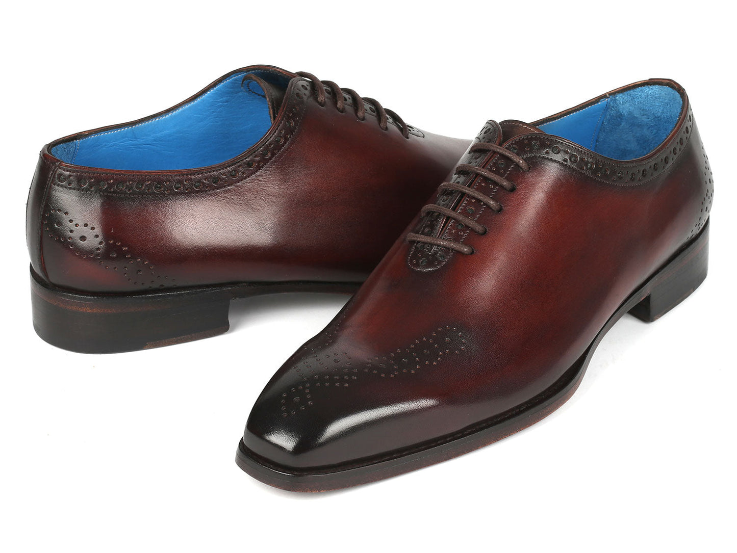 A pair of Paul Parkman Goodyear Welted Punched Oxfords in brown, crafted from intricately hand-painted calfskin featuring decorative perforations, lace-up closures, and a vibrant blue lining.