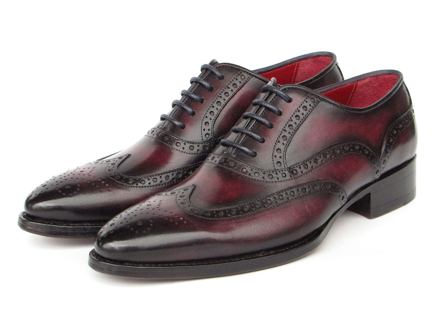 Presenting the Paul Parkman Bordeaux Burnished Goodyear Welted Wingtip Oxford Shoes - 66BRD94: a pair of polished, handmade shoes crafted from rich Bordeaux burnished leather with exquisite brogue detailing. They feature a striking red interior lining and sleek black laces. These elegant dress shoes are designed by Paul Parkman and constructed with Goodyear welted craftsmanship, ensuring both durability and timeless style.