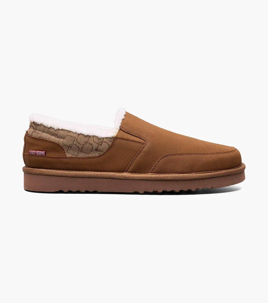 The Stacy Adams Coze Moc Toe Slip On in Tan Multi features a textured upper, plush faux shearling lining, and flat rubber sole, shown on a white background.