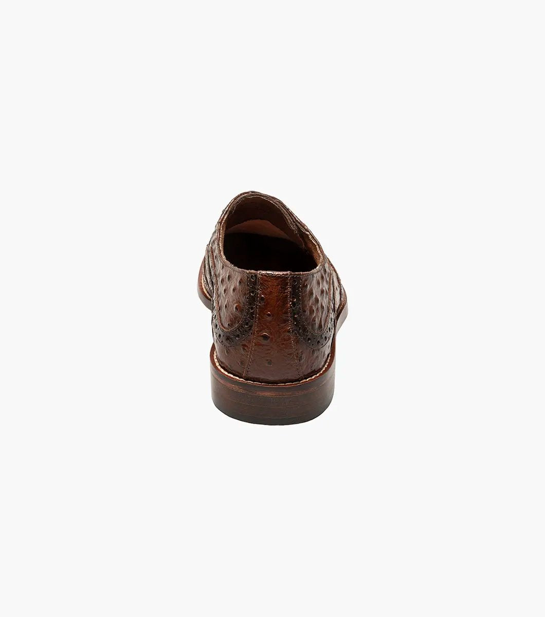 The Stacy Adams GENNARO Wingtip Oxford in cognac showcases a brown ostrich quill print leather design with intricate brogue detailing and a lace-up closure, complemented by anatomical arch support, offering an elegant side view.
