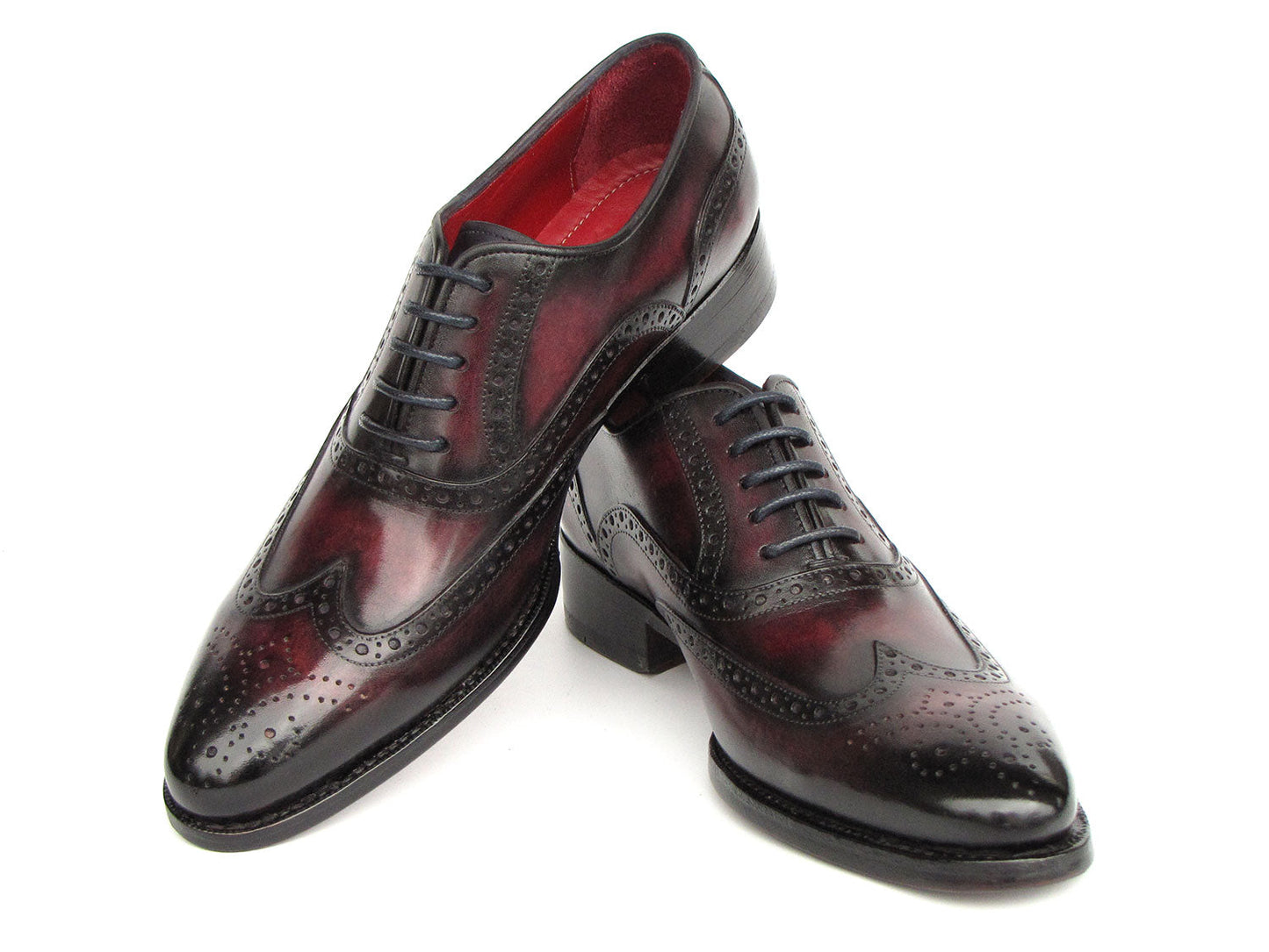Presenting the Paul Parkman Bordeaux Burnished Goodyear Welted Wingtip Oxford Shoes - 66BRD94: a pair of polished, handmade shoes crafted from rich Bordeaux burnished leather with exquisite brogue detailing. They feature a striking red interior lining and sleek black laces. These elegant dress shoes are designed by Paul Parkman and constructed with Goodyear welted craftsmanship, ensuring both durability and timeless style.
