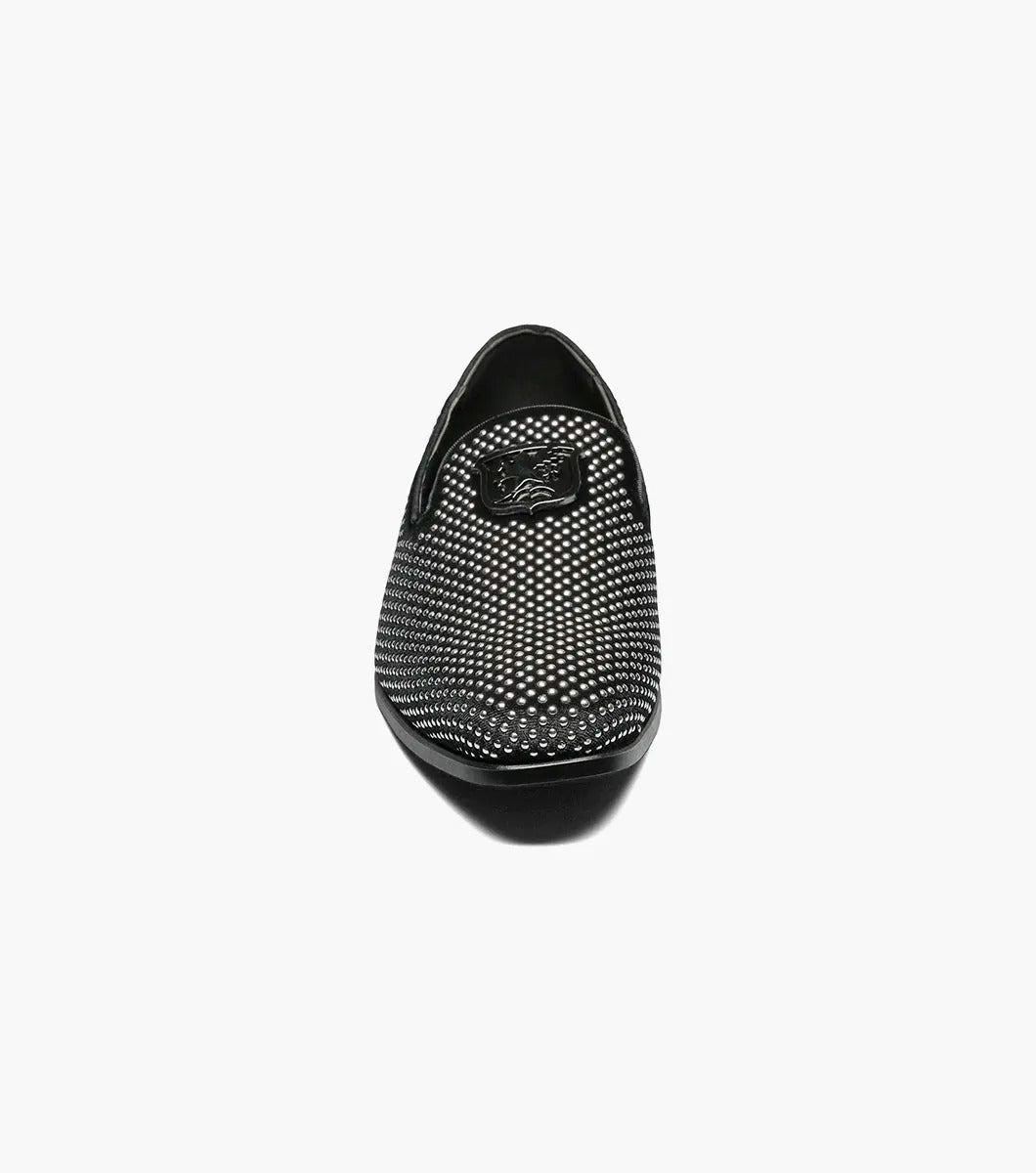 The STACY ADAMS SWAGGER Studded Slip On in black and silver, model 25228-042, is a loafer featuring striking silver studs and the Stacy Adams crest on the upper, exuding a sense of understated elegance.
