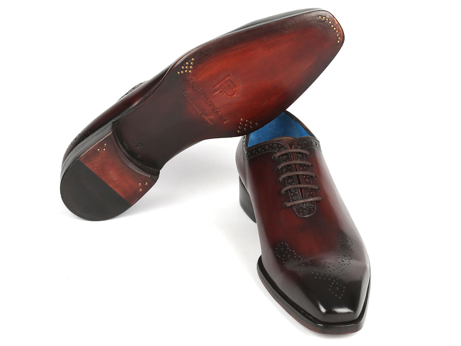 A pair of Paul Parkman Goodyear Welted Punched Oxfords in brown, crafted from intricately hand-painted calfskin featuring decorative perforations, lace-up closures, and a vibrant blue lining.