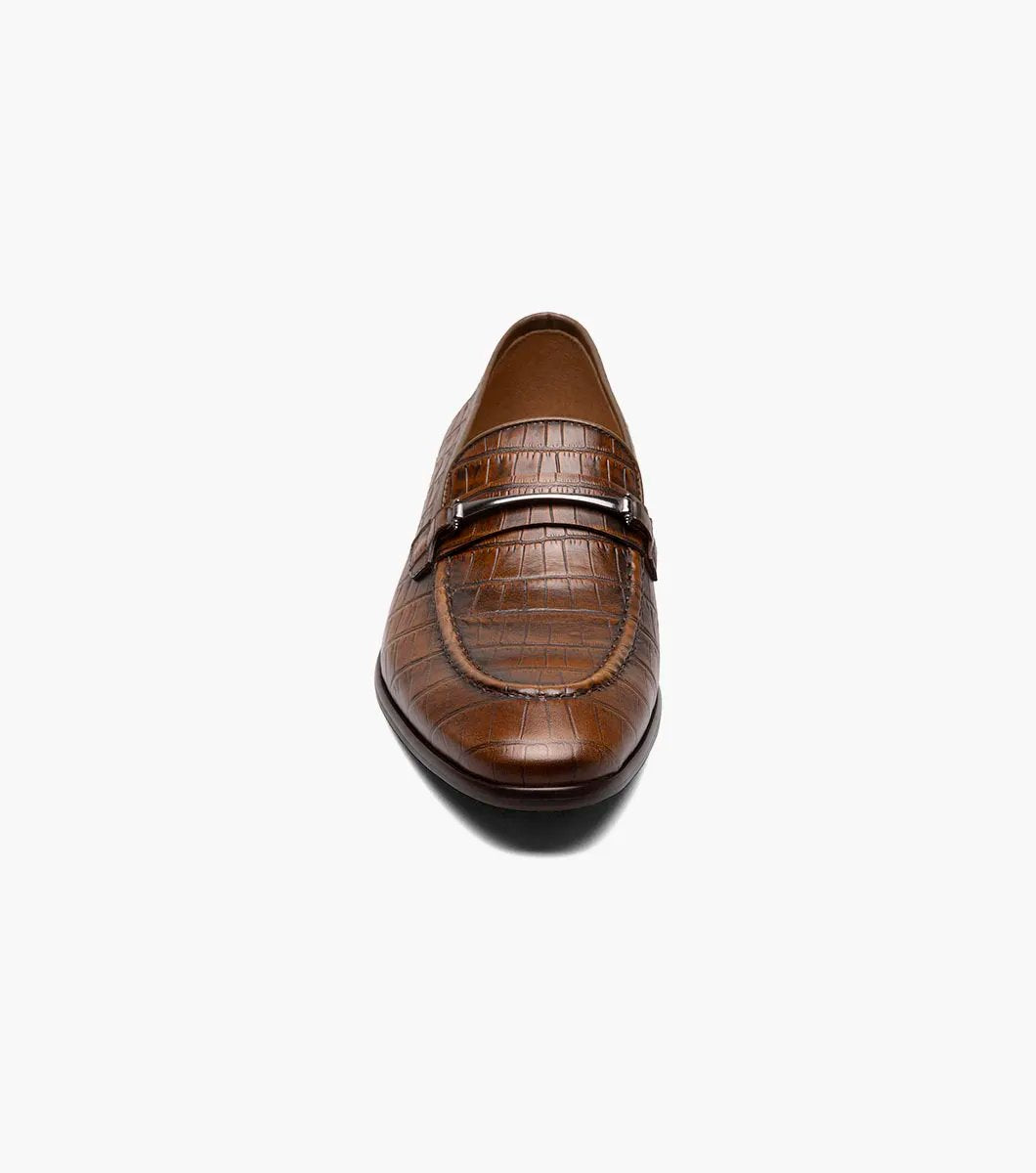 The STACY ADAMS Ferdinand Moc Toe Bit Slip On in Cognac features croco print leather, a decorative metal bit, and a cushioned memory foam footbed, displayed on a white background.
