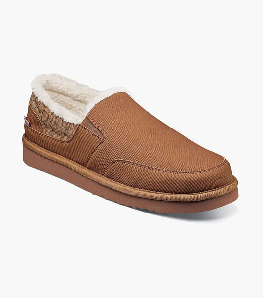 The Stacy Adams Coze Moc Toe Slip On in Tan Multi features a textured upper, plush faux shearling lining, and flat rubber sole, shown on a white background.