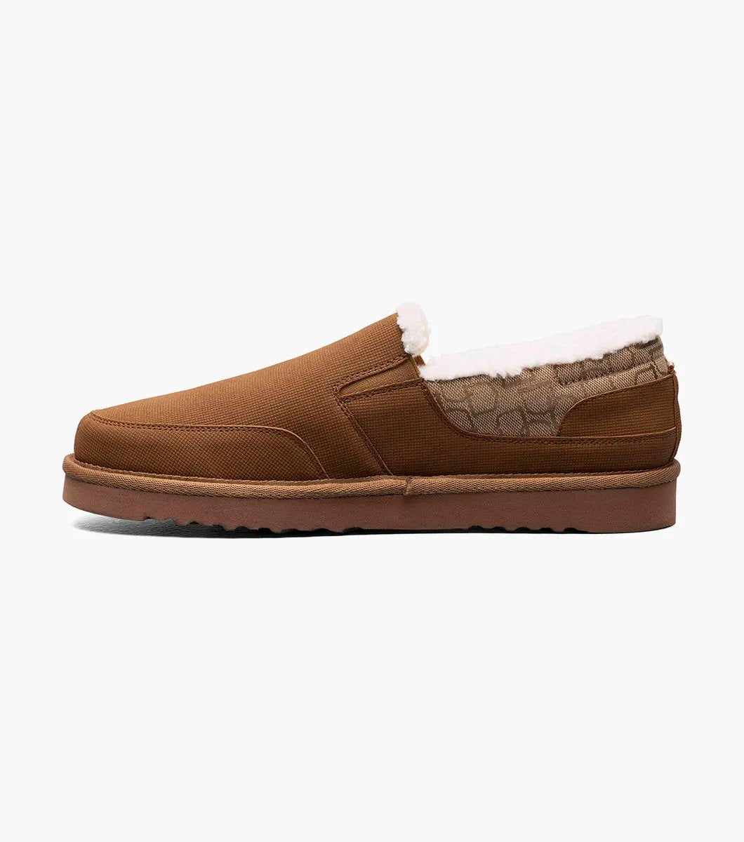 The Stacy Adams Coze Moc Toe Slip On in Tan Multi features a textured upper, plush faux shearling lining, and flat rubber sole, shown on a white background.
