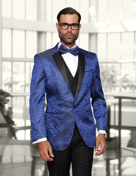 A man is dressed in the STATEMENT CLOTHING | BELLAGIO-ROYAL tuxedo, a creation by Statement Clothing. The exquisite ensemble in a royal blue pattern features a black lapel and bow tie, allowing him to stand out elegantly indoors against a blurred background.