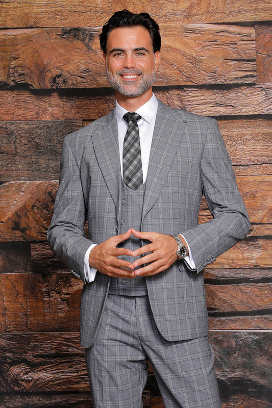 A man in the MANZINI Beverly Charcoal Suit with side vents smiles and clasps his hands, standing in front of a wooden textured background, showcasing the modern fit by Manzini elegantly.