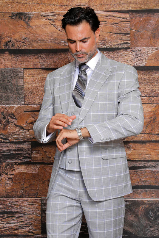 A person wearing a MANZINI Beverly Gray Suit with side vents and a modern fit checks their watch, standing against a wood-textured wall.