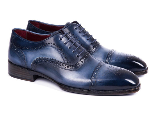 The Paul Parkman Cap Toe Oxfords Blue & Navy - 024-NVYBLU, crafted by Paul Parkman, are hand-painted leather shoes with decorative perforations and laces, elegantly displayed on a white background.