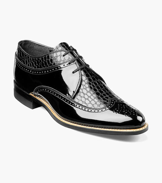 The Stacy Adams DAYTON Wingtip Oxford (Black, 00605-01) is a faux patent leather dress shoe with a low heel, lace-up closure, and textured hexagonal pattern on the upper.