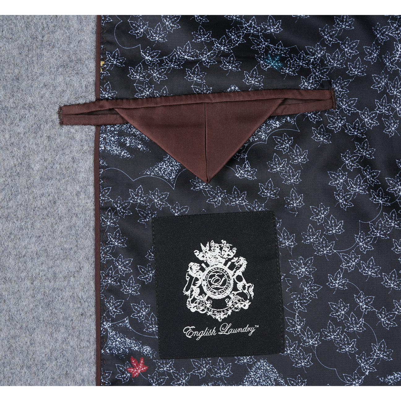 The ENGLISH LAUNDRY Wool Blend Breasted Light Gray Top Coat EL53-01-092 by English Laundry is a stylish single-breasted overcoat featuring three buttons and notched lapels. It pairs well with a white shirt and navy polka dot tie, making it the perfect versatile topcoat for any occasion.