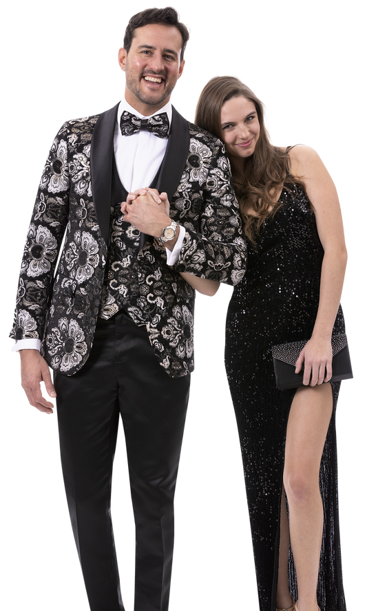 A man in the EJ Samuel Black Blazer J179, styled with a floral tuxedo and matching bow tie, stands smiling alongside a woman in a black sequined dress against a plain background.
