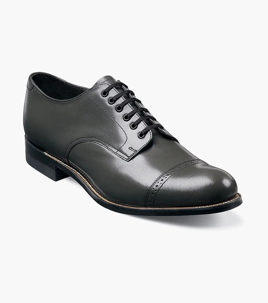 The Stacy Adams MADISON Cap Toe Oxford in steel gray is crafted from kidskin leather and features a lace-up closure, low stacked heel, and Goodyear welt construction for durability.