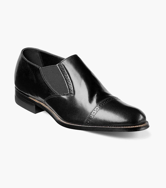 The Stacy Adams MADISON Cap Toe Slip On in black, designated as style number 00017-01, features a sophisticated cap-toe design with elastic side panels, complemented by a leather sole and sleek low heel.