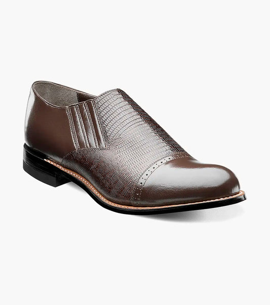 The Stacy Adams Madison Cap Toe Slip On in brown kidskin leather features an embossed pattern, elastic side panels, and a low black heel, shown as a single shoe on a white background.