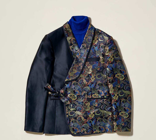 The Inserch Tied Floral Blazer BL207-01 Black is a slim-fit jacket with one side in plain black and the other in a vibrant floral jacquard pattern, expertly paired with a blue turtleneck for a striking look.