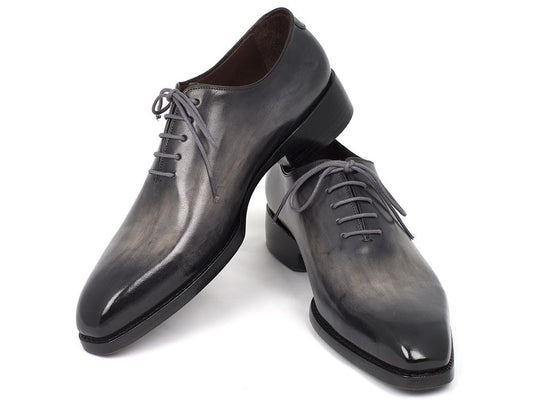 A pair of sleek Paul Parkman Goodyear Welted Wholecut Oxfords, hand-painted in glossy black and featuring gray laces, with one shoe standing upright and the other lying beside it.