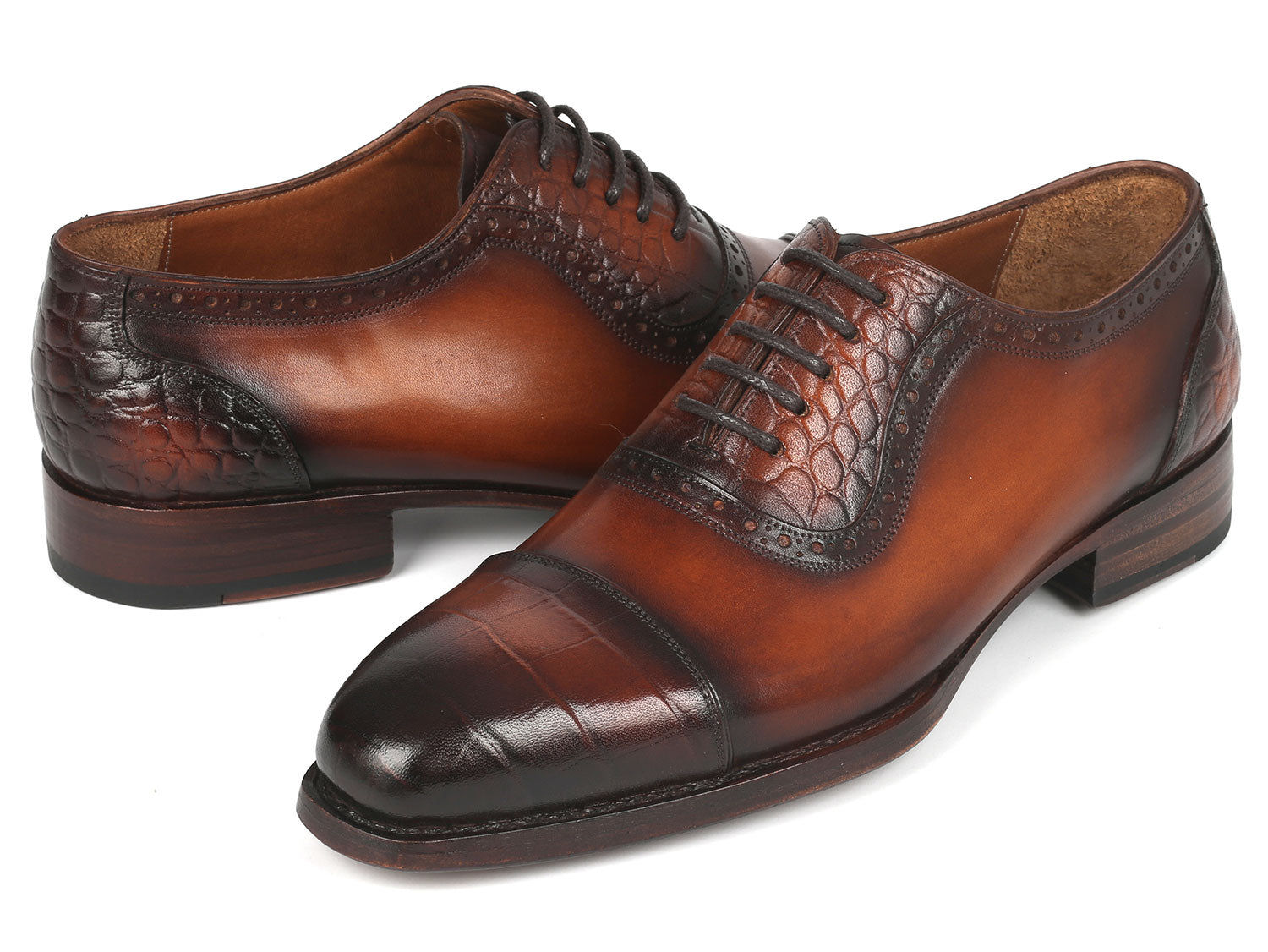 Introducing the Paul Parkman Goodyear Welted Cap Toe Oxfords in Brown - 9482-BRW: A meticulously handcrafted pair of shoes, distinguished by polished brown leather with black toe caps. These Oxford shoes showcase intricate brogue detailing and laces, designed for durability and comfort through expert craftsmanship.