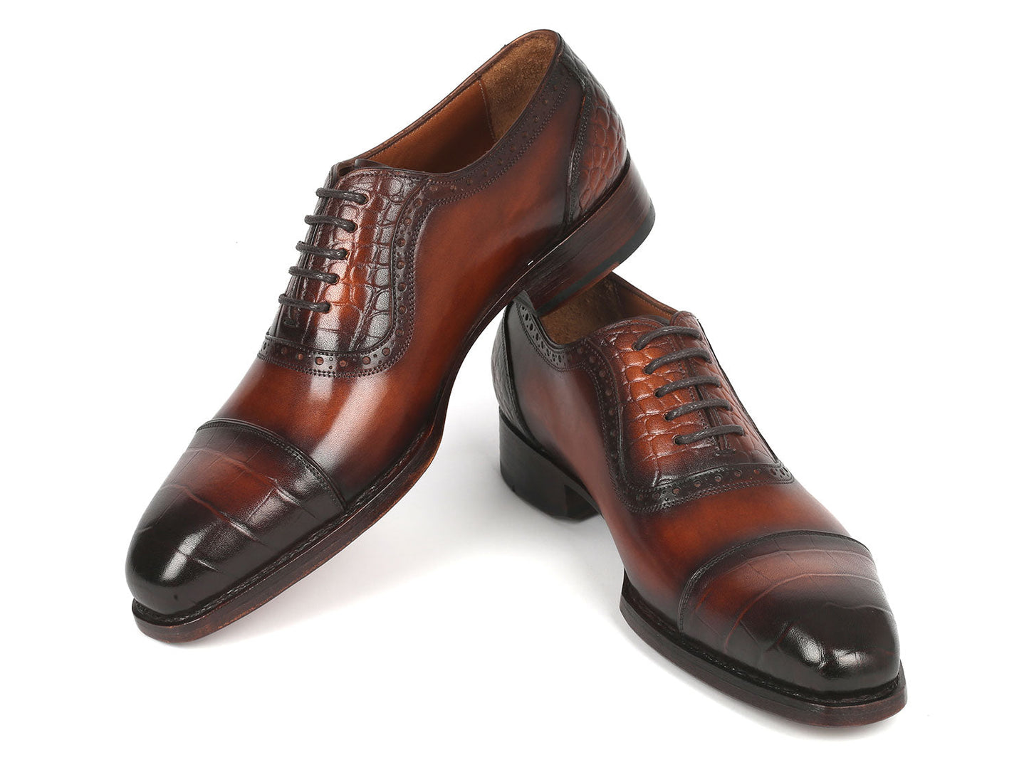 Introducing the Paul Parkman Goodyear Welted Cap Toe Oxfords in Brown - 9482-BRW: A meticulously handcrafted pair of shoes, distinguished by polished brown leather with black toe caps. These Oxford shoes showcase intricate brogue detailing and laces, designed for durability and comfort through expert craftsmanship.