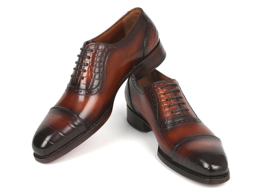 Introducing the Paul Parkman Goodyear Welted Cap Toe Oxfords in Brown - 9482-BRW: A meticulously handcrafted pair of shoes, distinguished by polished brown leather with black toe caps. These Oxford shoes showcase intricate brogue detailing and laces, designed for durability and comfort through expert craftsmanship.