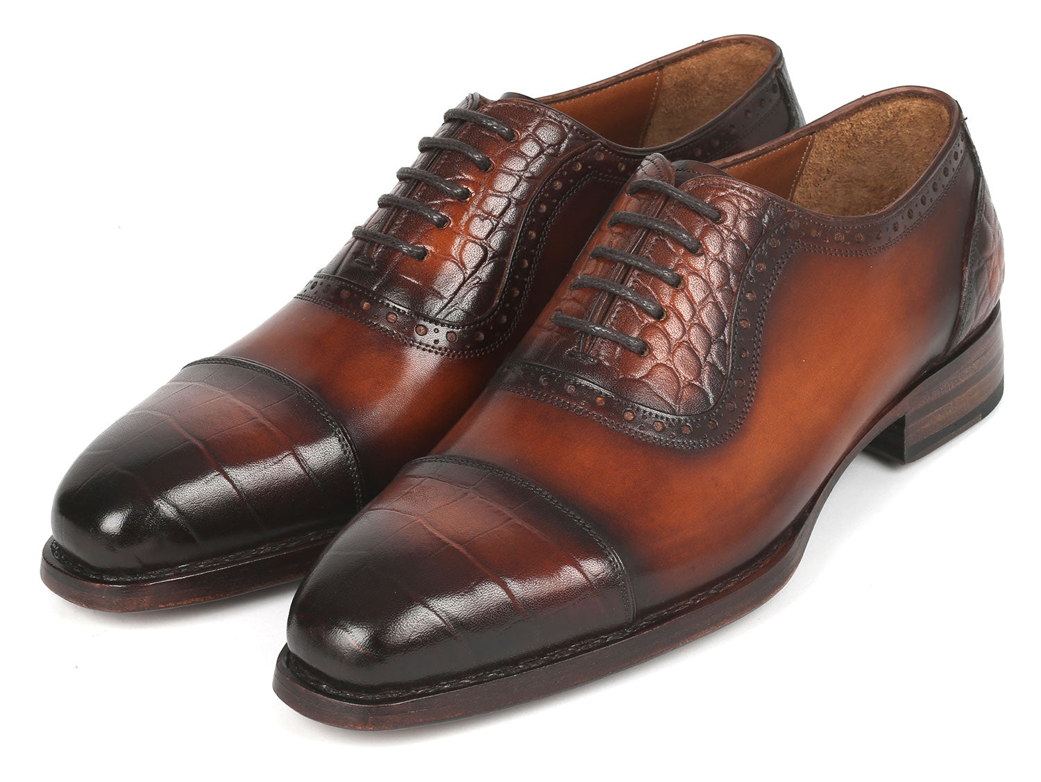 Introducing the Paul Parkman Goodyear Welted Cap Toe Oxfords in Brown - 9482-BRW: A meticulously handcrafted pair of shoes, distinguished by polished brown leather with black toe caps. These Oxford shoes showcase intricate brogue detailing and laces, designed for durability and comfort through expert craftsmanship.