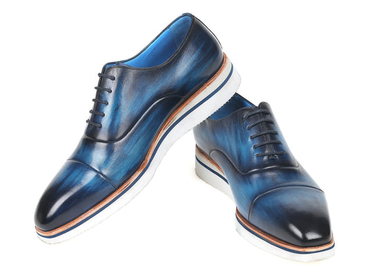 Introducing the Paul Parkman Smart Casual Oxfords in blue leather, featuring hand-painted calfskin with brown accents and white soles. These stylish shoes are arranged in a cross position and are ideal for smart casual occasions.