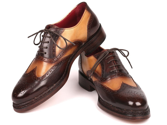 Paul Parkman wingtip oxfords, model 027-BJBRW, feature a brown and beige design with intricate perforations and laces. Crafted from supple calfskin leather using the Goodyear welted technique, these shoes are displayed with one resting atop the other.