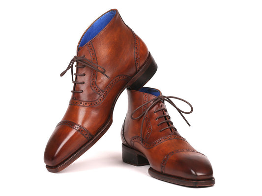 A pair of Paul Parkman Antique Brown Cap Toe Ankle Boots, artfully designed with brogue detailing and blue lining, exhibiting Goodyear welted construction. One boot stands upright while the other leans to the side, highlighting their sophisticated design and robust durability.