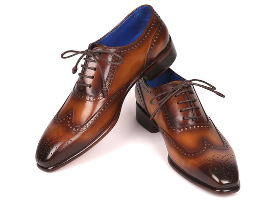 Introducing the Paul Parkman Handmade Wingtip Oxfords Brown - 711W03: these exquisite brogue shoes feature intricate decorative perforations, a striking blue interior lining, and matching brown laces. Expertly crafted by Paul Parkman, each pair is stylishly displayed with one shoe resting elegantly atop the other.