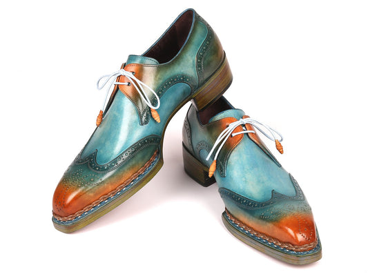 The Paul Parkman Norwegian Welted Wingtip Derby Shoes in Turquoise & Tobacco feature a vibrant leather design with gradient shades of blue, green, and orange. These shoes are adorned with white laces and decorative perforations, crafted from hand-painted leather.