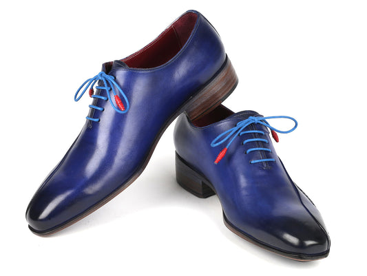 The Paul Parkman Blue Leather Oxford Shoes, featuring a side hand-sewn design with blue laces and red aglets, are stacked stylishly on a white background.