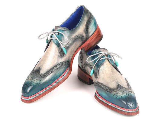 The Paul Parkman Norwegian Welted Wingtip Derby Shoes in Blue & Grey - 8506-BLU are hand-painted leather shoes featuring multicolored accents in teal, grey, and red. With decorative perforations and teal laces, these stylish shoes are showcased against a white background.