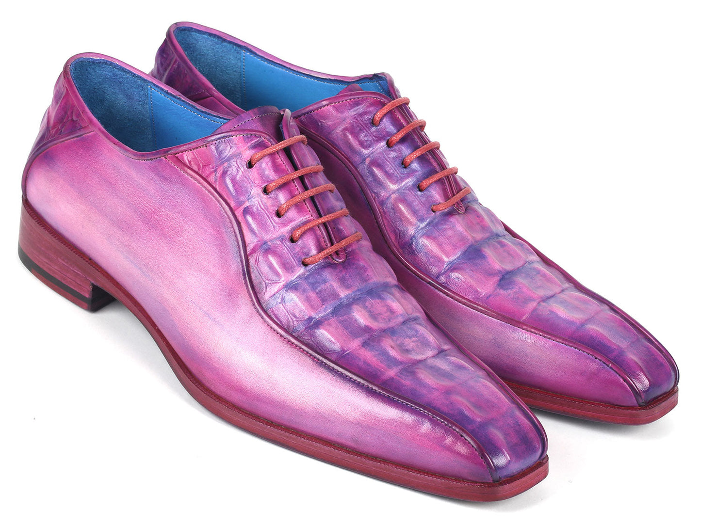 Introducing the Paul Parkman Purple Croco Textured Leather Bicycle Toe Oxfords - 94-277: a pair of handmade shoes crafted from shiny, lizard skin leather in a striking purple hue. Designed with a bicycle toe, these luxurious oxfords feature intricate blue lining and vibrant pink laces, elegantly displayed against a clean, white background.