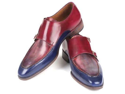 Against a white background, the Paul Parkman Blue & Bordeaux Double Monkstraps - SW533YR are positioned at an angle. These exquisite leather shoes, featuring reddish-brown tops and navy blue toe caps with decorative buckles, are crafted from hand-painted calfskin for a bespoke touch by Paul Parkman.