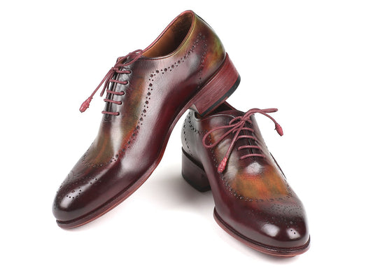 A pair of Paul Parkman Opanka Construction Green & Bordeaux Oxfords - 726-GRE-BOR is elegantly displayed on a white background. One shoe stands upright while the other leans gracefully against it, showcasing exquisite decorative perforations and meticulous craftsmanship.