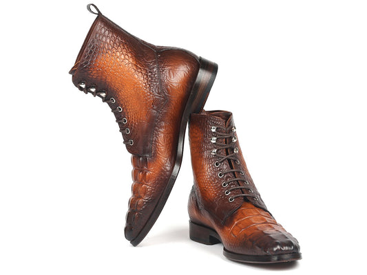 A pair of Paul Parkman brown croco embossed leather lace-up boots (BT744-BRW), elegantly crafted and made-to-order. One boot stands upright, while the other leans against it, highlighting their distinctive charm.
