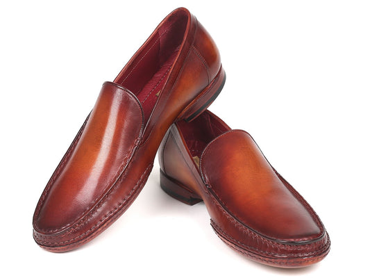 A set of Paul Parkman Hand-Sewn Moccasins in brown, created using hand-painted leather, displays one shoe slightly elevated and overlapping the other.