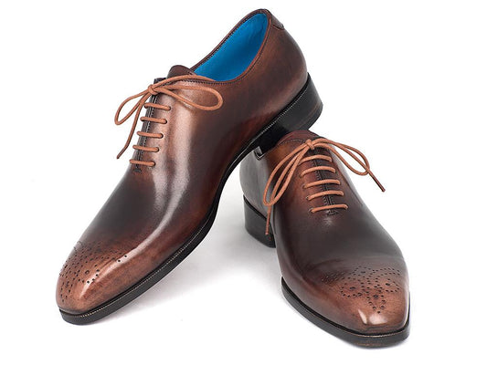 A pair of Paul Parkman Camel & Brown Wholecut Oxfords – KR254CML, exquisitely handmade with antique finished leather and adorned with decorative perforations and laces, elegantly displayed on a white background.