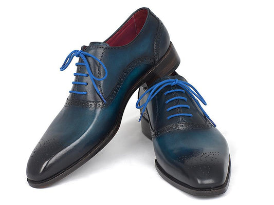 The Paul Parkman Blue & Navy Medallion Toe Oxfords – FS88VA are a striking pair of polished blue leather dress shoes with matching blue laces and decorative perforations. These handmade oxfords feature hand-painted leather and a stacked wooden heel, offering a unique touch to their timeless elegance.