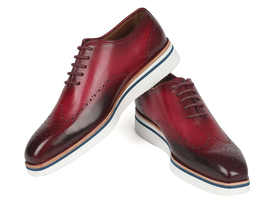 Presenting the Paul Parkman Men's Smart Casual Wingtip Oxfords in Bordeaux (188-BRD). These Oxford-style shoes feature a rich red leather with decorative perforations and brown accents, complemented by white soles. Perfect for a smart casual look, they are stylishly displayed with one shoe slightly elevated above the other.