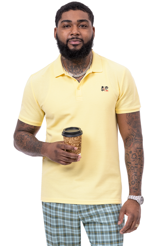 A bearded man in a yellow polo shirt holds a paper coffee cup. He has tattoos on his arms and is wearing EJ Samuel Mint Plaid Pants PL83 by EJ SAMUEL.