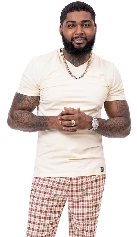 A tattooed man is wearing a light-colored shirt and the modern-fit EJ Samuel Burg/Tan Plaid Pants PL84, standing with his hands clasped.