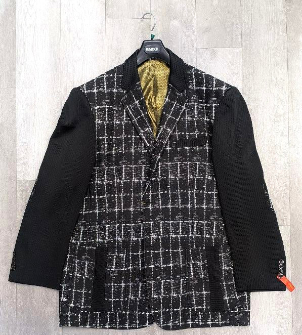 The Inserch Blazer 5062-01 in black, featuring a sleek black and white plaid design and sophisticated black sleeves, is displayed elegantly on a hanger against a light wooden background, emanating timeless charm. Exclusively available in size 3XL as a final sale item from the brand Inserch.