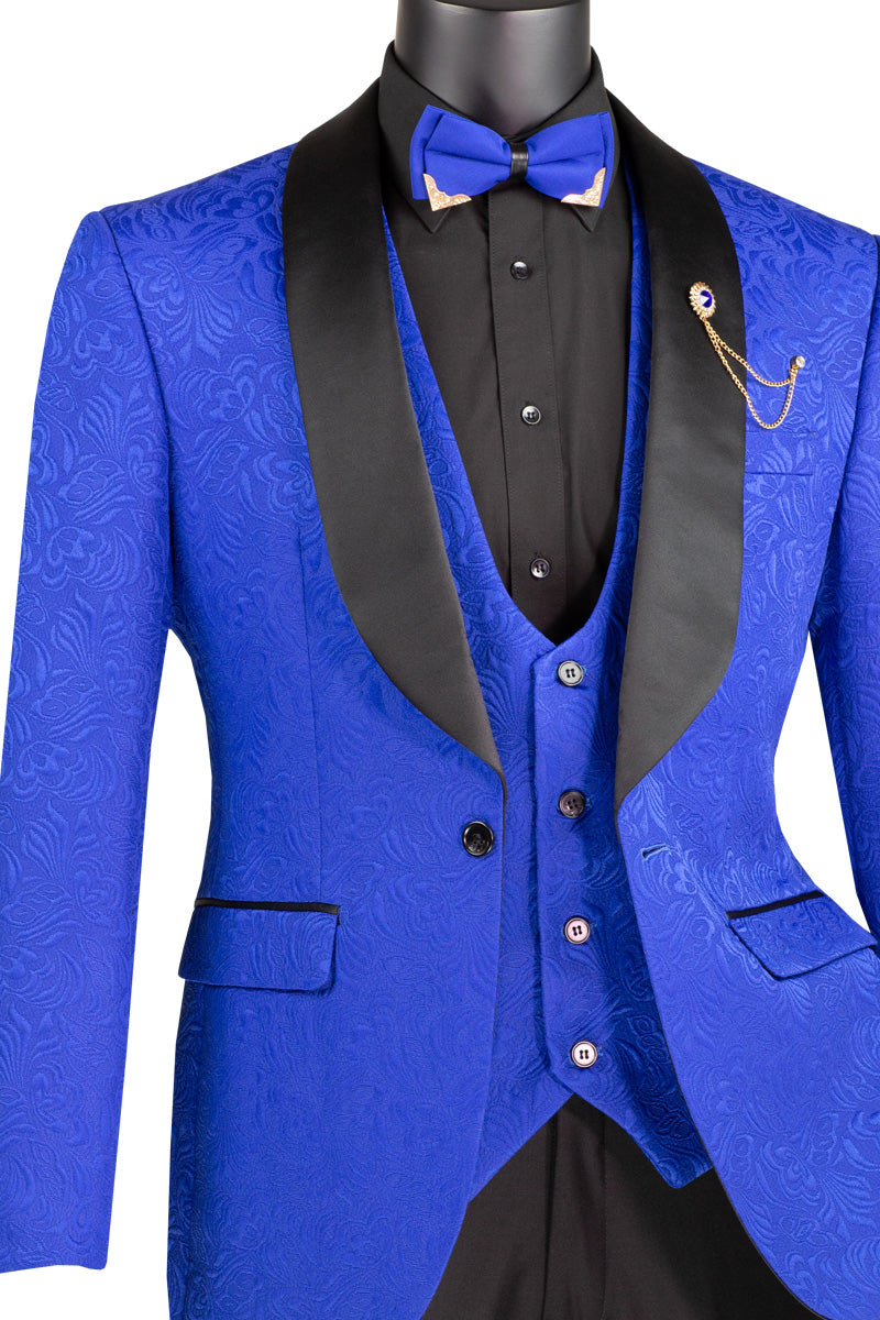 The Vinci Suits Slim Fit 3 Piece Single Button Jacquard Fabric Tuxedo (Royal) TVSJ-1 flaunts a blue patterned design with black lapels, sleek blazer, and gold-buttoned waistcoat. Paired with a black shirt, blue bow tie, and gold chain, it's elegantly showcased on a mannequin.